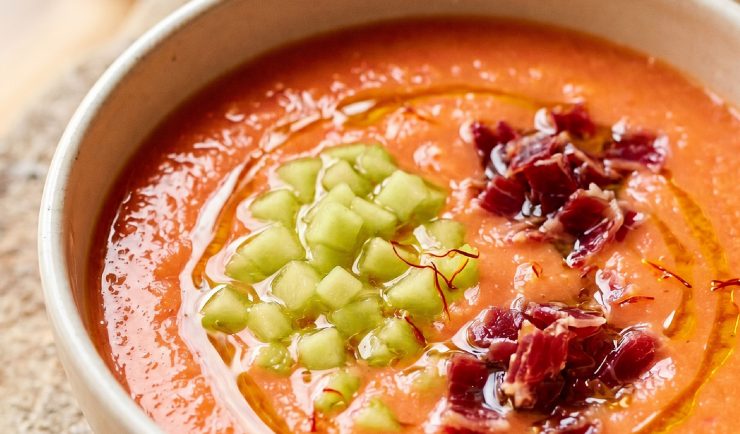 Plato hondo con salmorejo de melón amarillo decorado con hebras de azafrán Antonio Sotos, crujiente de jamón ibérico y un hilo de aceite de oliva.